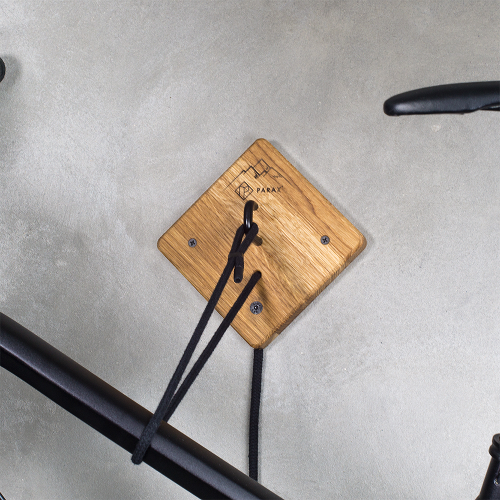 Hauptteil von Fahrrad Wandhalterung U-RACK aus Holz mit schwarzer Kordel hält schwarzes Fahrrad an grauer Wand
