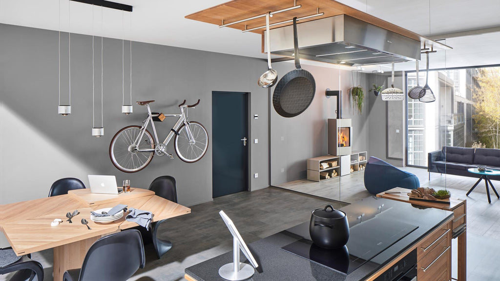 Schwarze Fahrrad Wandhalterung D-RACK mit Olivenholzfront und silbernem Fahrrad vor grauer Wand in modernem Loft